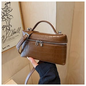 Close-up of brown crocodile texture on a mini square bag with silver metal zippers