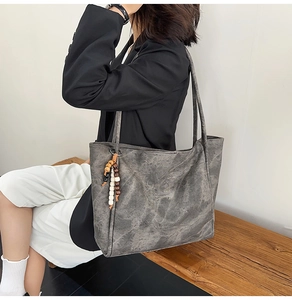 Detail of dark gray tote bag with marble texture and decorative beaded charm