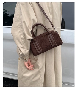 Detail of dark brown suede bowling bag with top handles and detachable shoulder strap