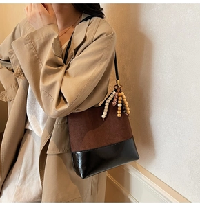 Détail d'un sac cabas marron mat avec bordure noire et pendentif décoratif en perles de bois