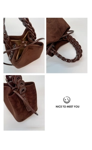 Detail view of coffee suede bucket bag with leather chain handle and drawstring closure