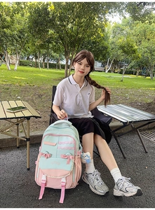 Close-up of pastel green and pink school backpack with lace, bow, and WIND embroidery