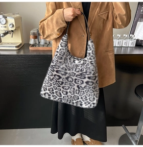 Detailed texture of leopard print plush tote bag with black strap in a lifestyle setting