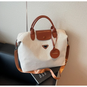 Detail of canvas travel tote with leather handles, metal hardware and nylon strap