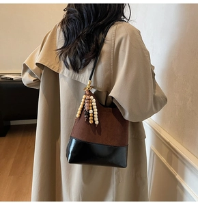 Detail of suede bucket bag with contrast leather base and ethnic beaded tassels