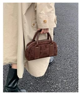 Detail of dark brown suede bowling bag with leather handles shown in a street style look