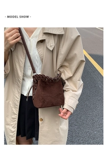 Brown suede bucket bag with woven chain detail and shoulder strap on model in trench coat