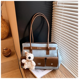 Detail of blue tote bag with brown leather accents and metal twist lock pocket
