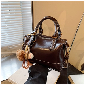Detail of vintage dark brown oil wax leather pillow bag with cute bear charm