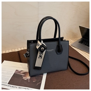 Détails de la texture du sac en similicuir gris avec poignées rondes noires et logo
