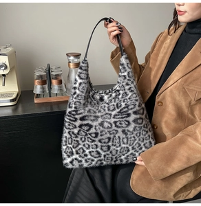 Close-up of leopard print plush tote bag with black leather handle shown on model