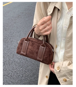 Close-up of brown suede Boston handbag texture and leather handle in a street setting