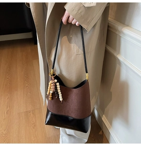 Détail d'un sac cabas vintage en cuir mat avec pompon en perles de bois et métal doré