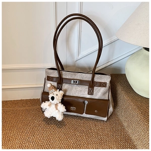 Detail of vintage canvas tote bag with leather straps and cute plush bear charm