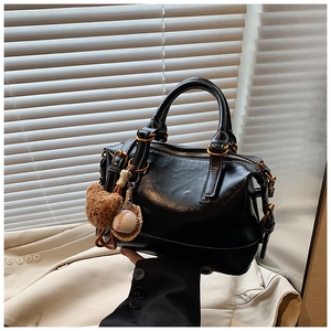 Detail view of a black glossy Boston bag with golden hardware and cute bear charms