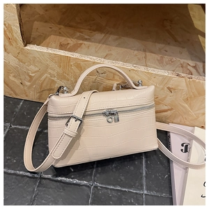 Detail of beige crocodile embossed handbag with top handle and golden double zippers