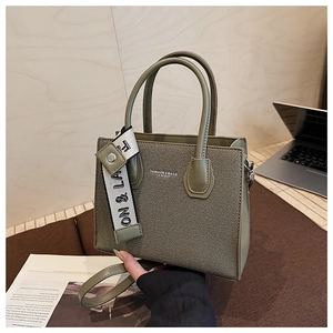 Détail du sac cabas vert olive en cuir avec breloque en toile et bandoulière amovible
