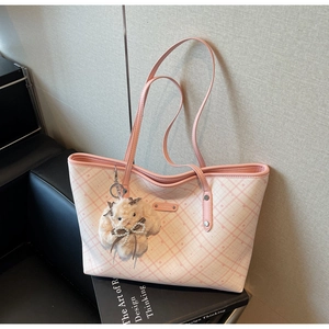 Dettaglio della borsa tote a quadri rosa con ciondolo a coniglio e finitura testurizzata