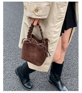 Detail of dark brown suede bucket bag with matching chain handle and drawstring closure