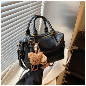 Detail of black Boston bag with vintage gold hardware and a cute teddy bear charm