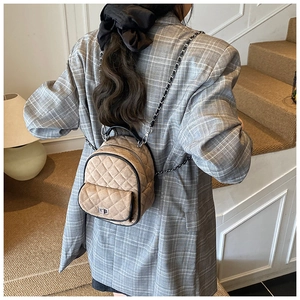 Close-up of khaki quilted mini backpack with silver metal chains and diamond pattern