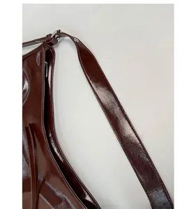 Close-up of the dark brown glossy leather texture and silver metal buckle on the backpack