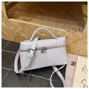 Detailed macro view of the white faux crocodile embossed texture and silver zipper on the handbag