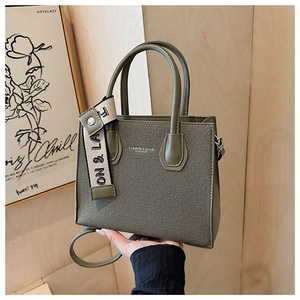 Gros plan sur la texture en toile vert olive et les poignées en cuir du sac carré chic