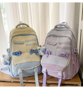 Detail of canvas school backpack with lace bow, WIND embroidery and bear pendant