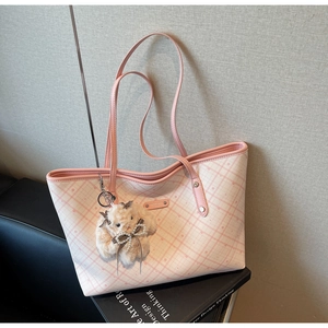 Dettaglio della borsa tote a quadri rosa con ciondolo a coniglio su panca nera