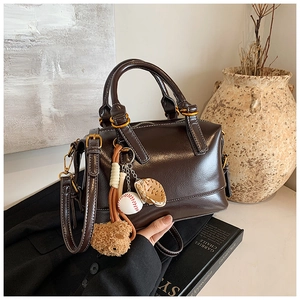 Detail of dark brown glossy Boston bag with vintage gold hardware and baseball charms