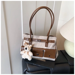 Detail of canvas tote bag with brown leather straps and cute white bear plush charm