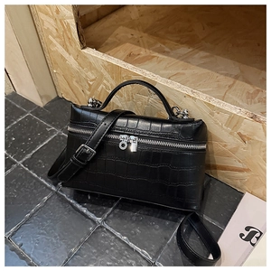 Detail of black crocodile texture box bag with silver zippers and top handle