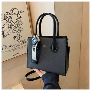 Détail du sac cabas en cuir noir texturé avec poignées et pendentif de mode chic