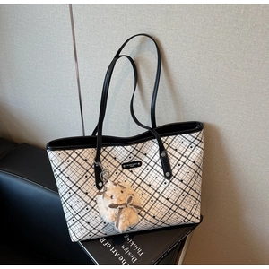 Dettaglio di una borsa tote a scacchi bianchi e neri con ciondolo a coniglio e logo