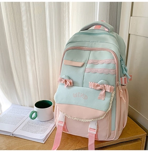 Detail of mint green and pink backpack featuring lace trim, ribbon bow and WIND embroidery