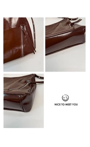 Detail of dark brown glossy patent leather backpack with silver zippers and metal eyelets