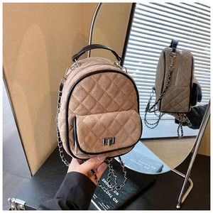 Close-up of quilted suede mini backpack featuring a metal turn-lock and chain strap