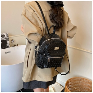 Dettaglio mini zaino nero a trama intrecciata con logo in metallo e tasca con cerniera