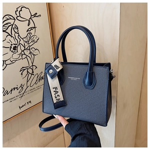 Détail d'un sac cabas bleu marine avec texture tissu-cuir et breloque à lettres FASH