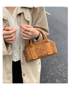 Close-up of brown suede Boston bag with leather handles and premium metal zipper detail