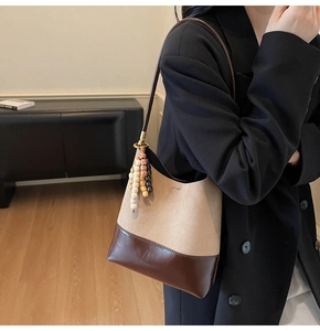 Détail du sac bandoulière en daim vintage avec finitions en cuir brun et pompon perlé