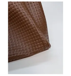 Macro detail of the woven dark brown leather texture on a stylish tote bag