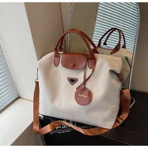 Detail view of large canvas travel tote with leather handles and mirror reflection