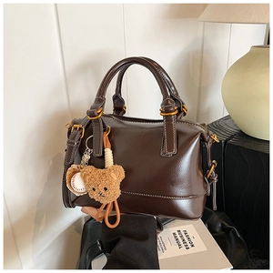Detail of vintage brown Boston bag with glossy finish and cute bear charm pendant