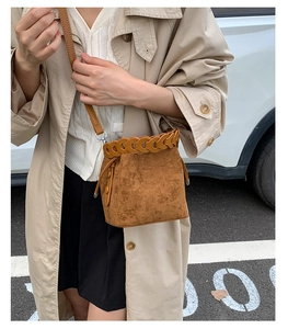 Close-up of caramel suede bucket bag featuring woven leather trim and drawstring detail