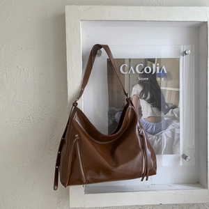 Macro detail of brown leather tote bag with silver side zippers in a minimalist display