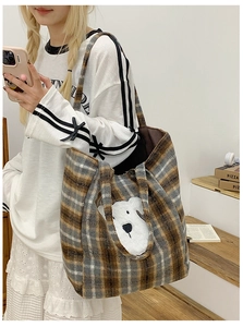 Detail of vintage plaid tote bag with cute plush puppy patch shown on a shoulder
