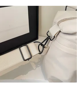 Detail of durable black metal swivel hook and adjustable nylon strap on beige crossbody bag