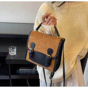 Detail of vintage matte color-block messenger bag with dual buckles and smooth texture